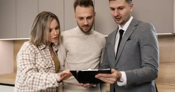 un couple et un agent immobilier regardent tous vers une tablette
