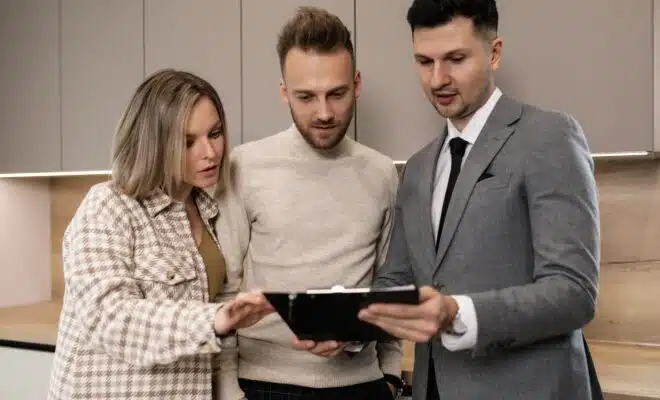 un couple et un agent immobilier regardent tous vers une tablette