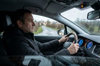 Conducteur de nuit en Anjou regardant une route mouillée depuis son habitacle en heure d'hiver