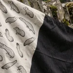 Gros plan sur le drapeau breton Gwenn-ha-du avec les onze hermines visibles sur tissu en lin accroché à un mur en pierre