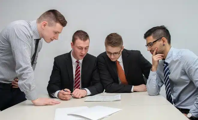 four men looking to the paper on table