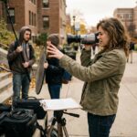 Étudiante en cinéma dirigeant un tournage pédagogique en extérieur sur un campus universitaire