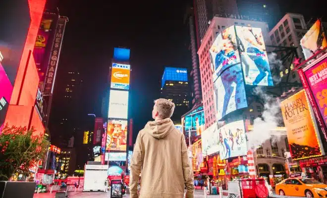 man standing on road infront of high-rise buildi